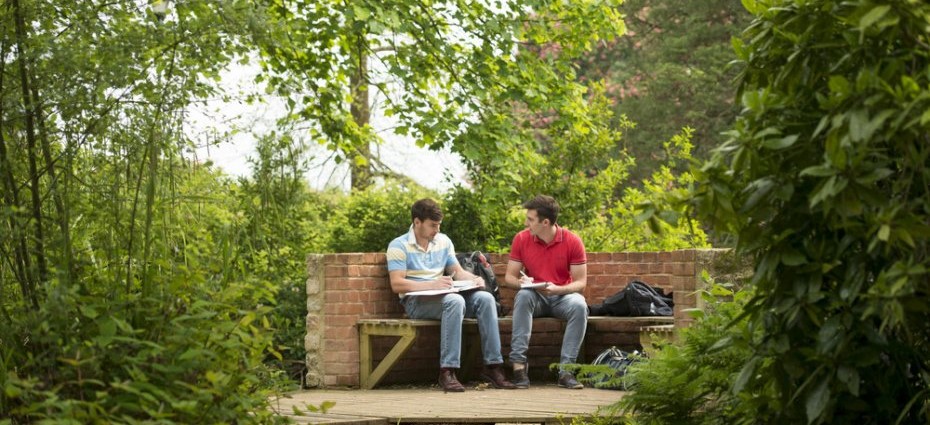 two students sitting in a garden on campus