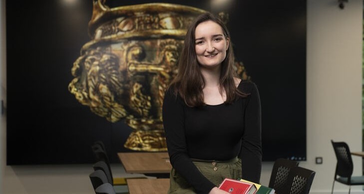 student sitting on a desk holding books