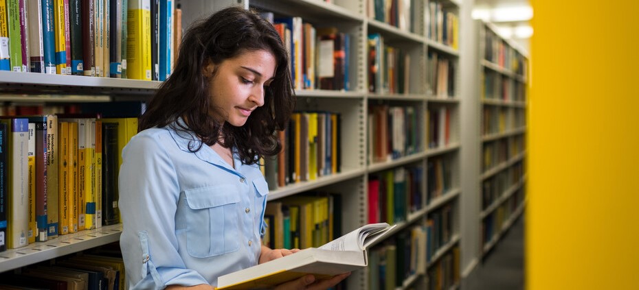 student reading a book in the library