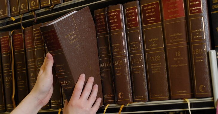 student taking a law book off a shelf