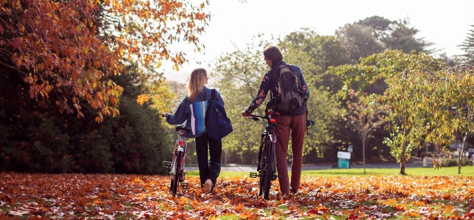 two students pushing a bike to campus