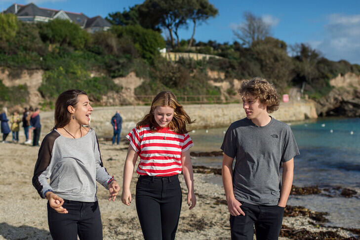 Three students chatting and walking along the beach