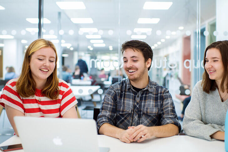 Three students at a laptop in the library