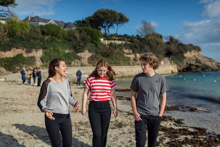 three students walk along the beach