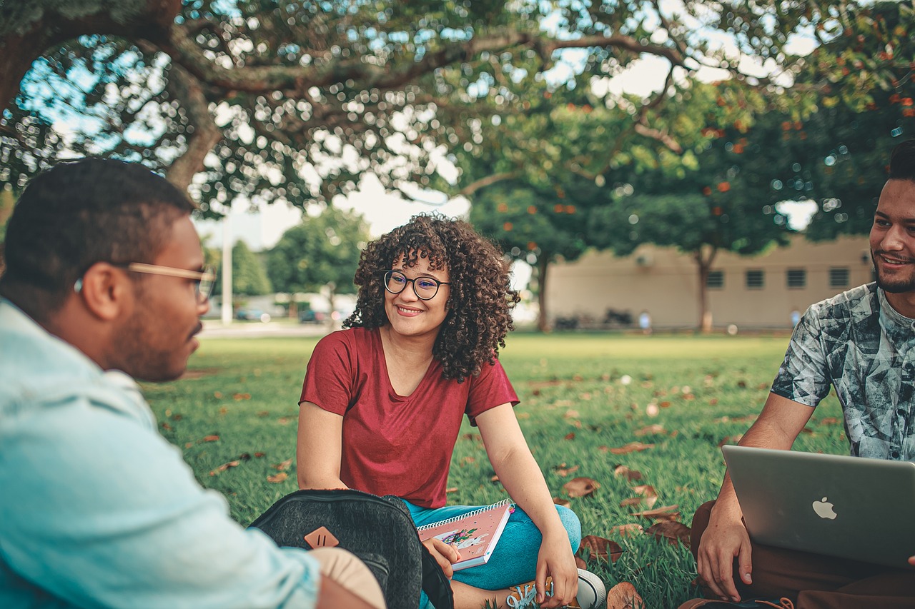 Students sitting on grass and smiling