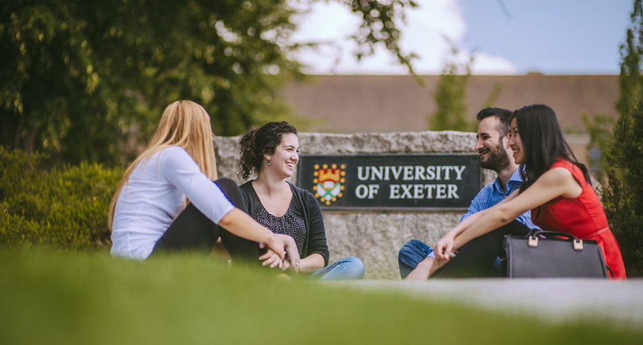 four students sitting by Exeter rock
